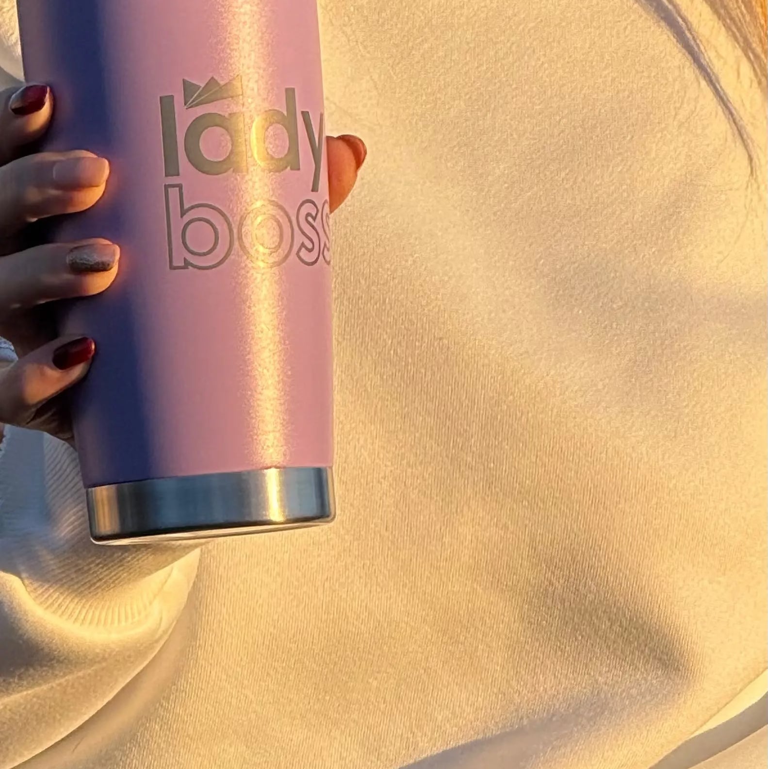 Person holding a pink tumbler with 'lady boss' text.