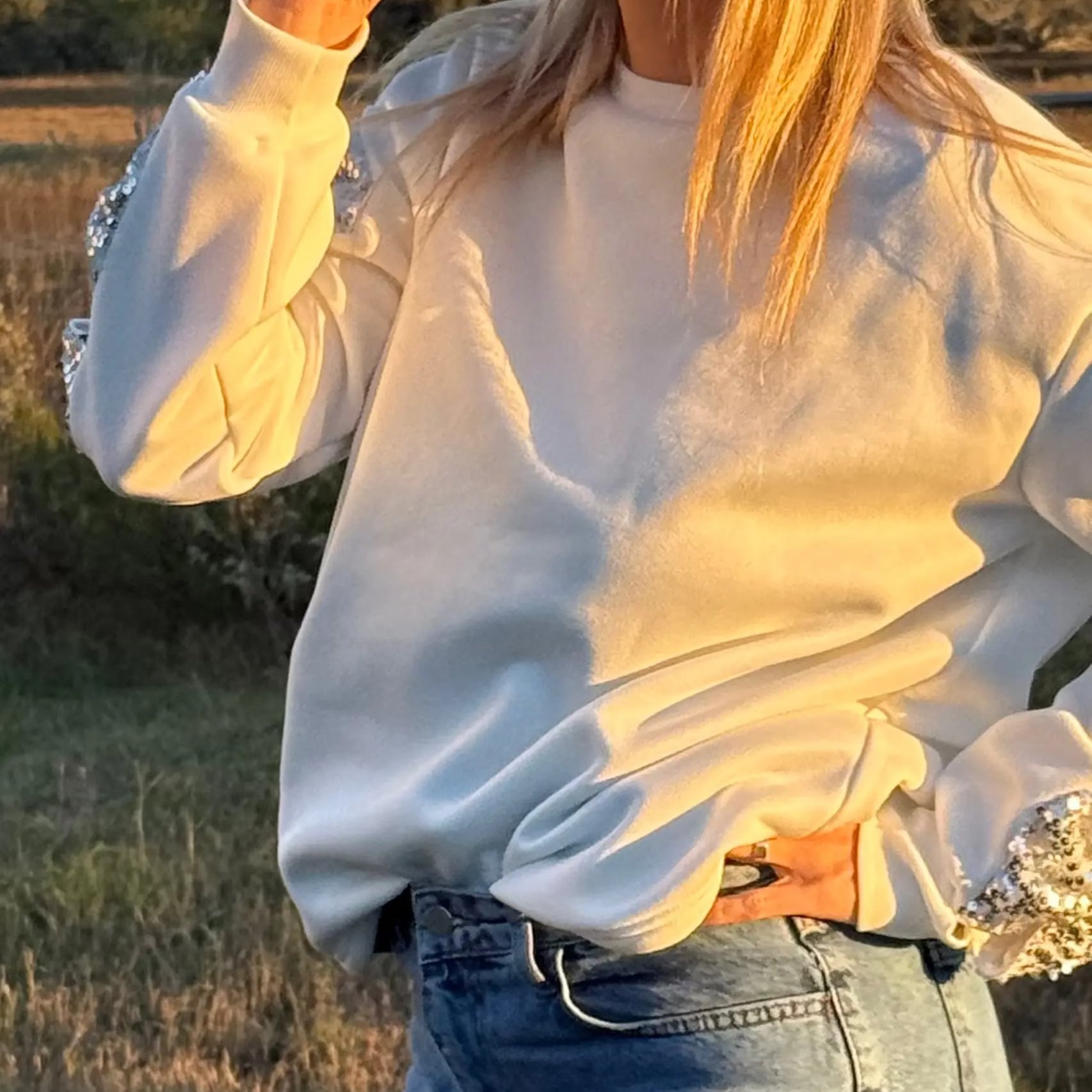 Person drinking from a pink cup in a field at sunset
